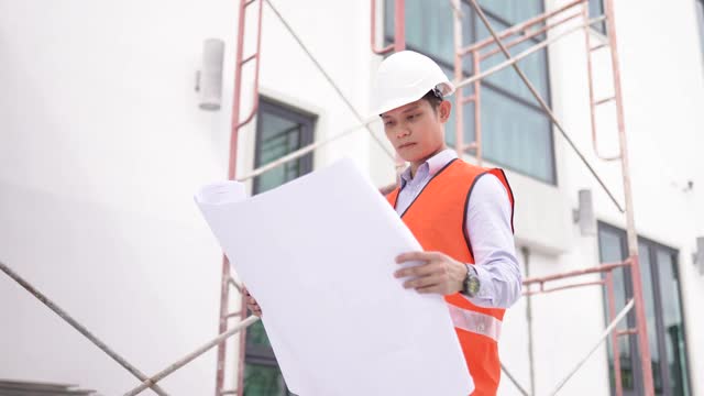 亚洲华人建筑师在工地上用蓝图演示施工进度视频下载