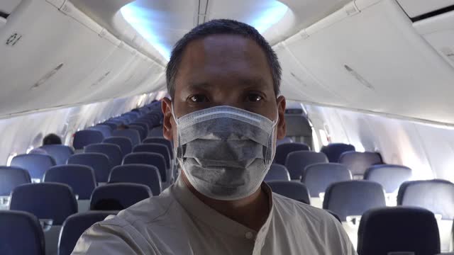 亚洲男子在飞机上戴面具视频素材