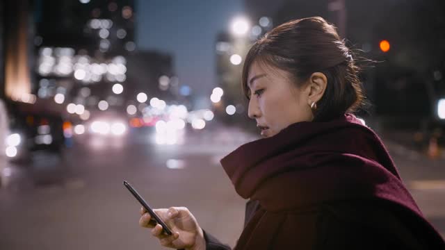 一个女人在晚上等车的时候用手机视频素材