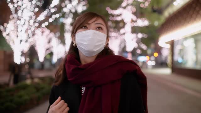 带着保护面罩的妇女手持可重复使用的购物袋行走在城市街道上的肖像视频下载