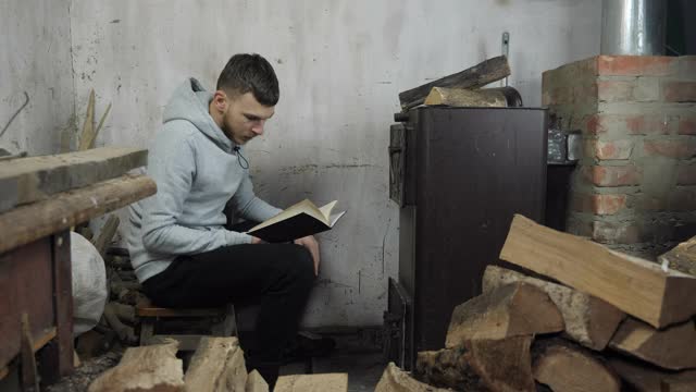 男人在壁炉旁看书，扔木柴。男把松木扔进烤炉。传统乌克兰正宗烤箱视频素材