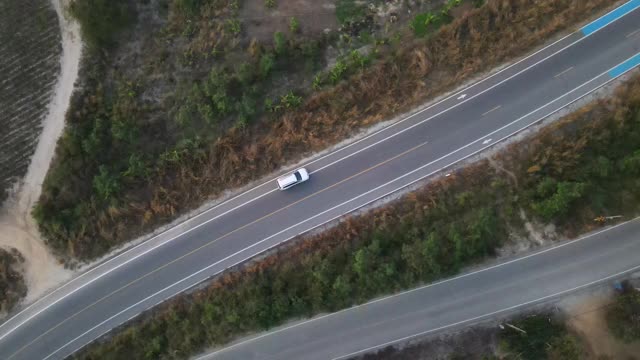 宽阔的无人机镜头跟踪一辆汽车在空旷的道路上被美丽的城外包围。视频素材