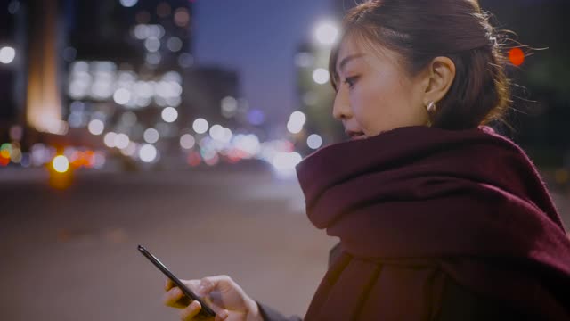 一个女人在晚上等车的时候用手机视频素材