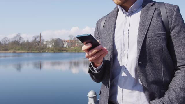 年轻的城市职业商人使用智能手机在公园散步视频素材