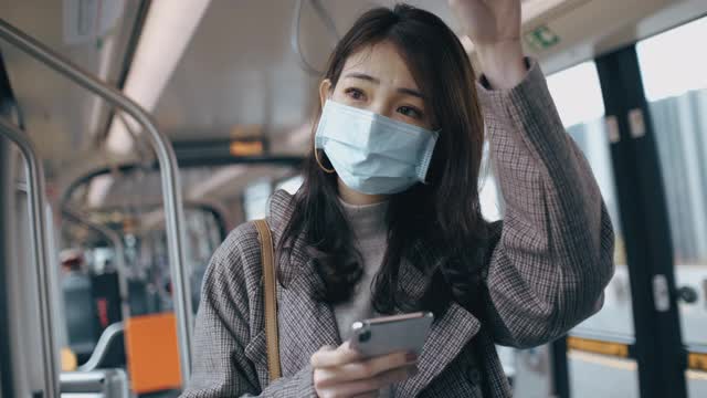 年轻女子在乘坐地铁时使用智能手机视频下载