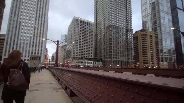 摇摄的人走在金属结构附近的摩天大楼的城市-芝加哥，伊利诺伊州视频素材