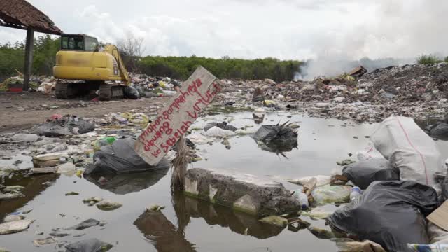 装满冒烟垃圾的垃圾堆，黄色的拖拉机和腐烂的废物的水池——巴厘岛的努沙佩尼达和龙目岛视频素材