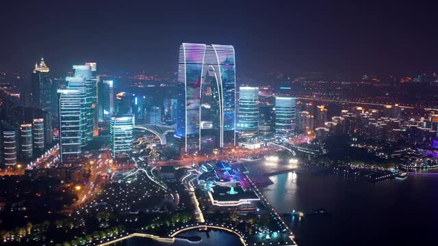 空中摇摄现代城市夜间灯火通明的建筑物，无人机飞过金鸡湖的天空-苏州，中国视频素材
