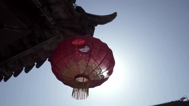 在晴朗的日子里，中国苏州，在晴朗的蓝天下，红色的中国灯笼悬挂在屋顶上视频素材