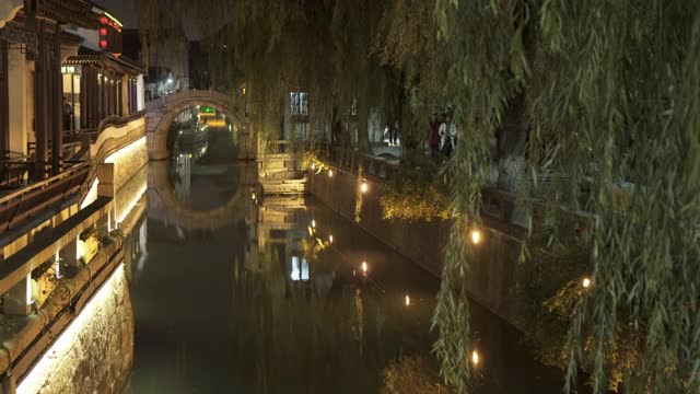 中国苏州，夜间在城市建筑中拍摄的照明运河视频素材