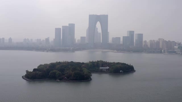 空中拍摄金鸡湖上的树木对着建筑物，无人机对着天空在城市附近飞行-苏州，中国视频素材