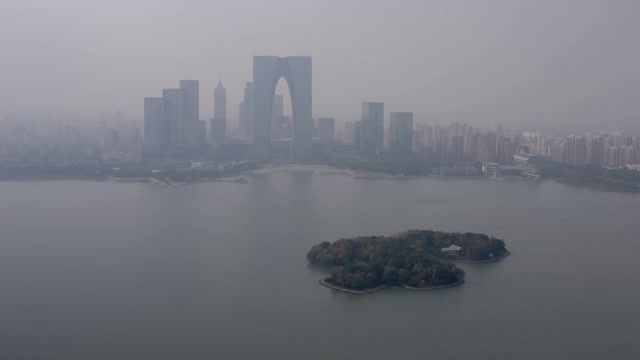 航拍金鸡湖上的绿岛对着建筑物，无人机对着天空飞近城市景观-苏州，中国视频素材