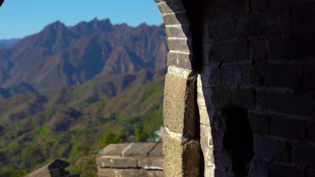 斯坦尼康镜头拍摄的中国长城，在山的一侧上升在一个开始下降。摄像头通过瞭望塔的通道，显示了从墙上的窗户看到的景色视频素材
