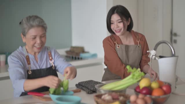 亚洲华人美丽的女人和她的母亲准备做饭为家人在厨房柜台视频素材