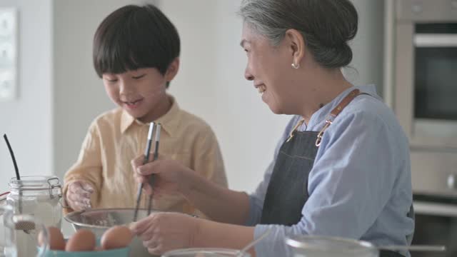 6岁的亚洲华人男孩在厨房柜台上用面粉烘焙，帮助祖母准备食物视频下载