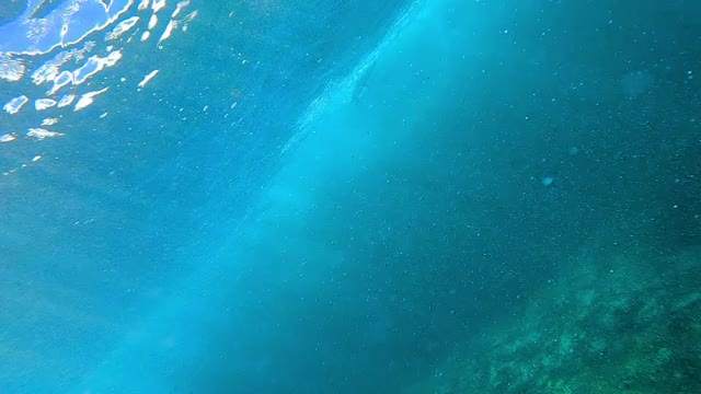 在水下看着一个冲浪者的剪影飞过破浪顶部与阳光反射通过洋面-瓦胡岛，夏威夷视频素材