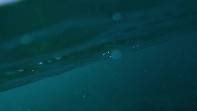 戏剧性的水下一个巨大的海浪滚动和破碎，与深蓝色的水，发光的泡沫和一个冲浪者飞过表面之上-瓦胡岛，夏威夷视频素材