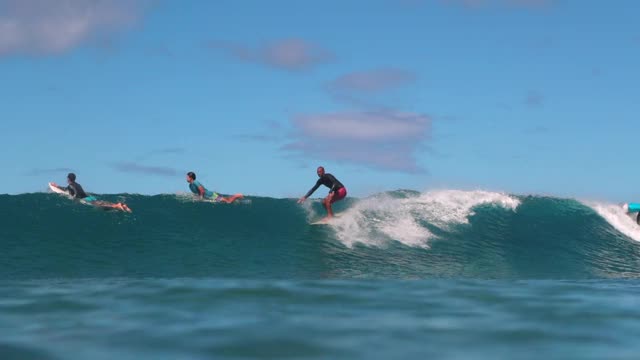 慢镜头平移拍摄的熟练男子蹲而冲浪的波浪-瓦胡岛，夏威夷视频下载
