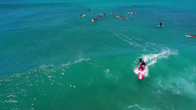 空中慢镜头拍摄的人冲浪，而溅在海浪上，无人机在晴朗的一天冲浪者在绿松石海-瓦胡岛，夏威夷视频下载
