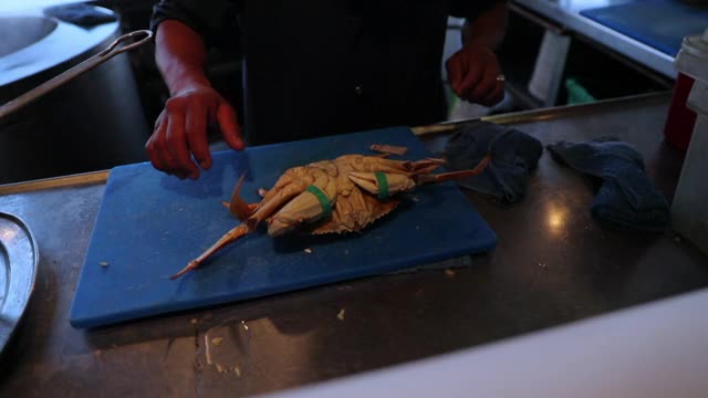 在加州旧金山的一家餐馆里，厨师在蓝色的砧板上摆弄绑着的螃蟹的慢动作镜头视频下载