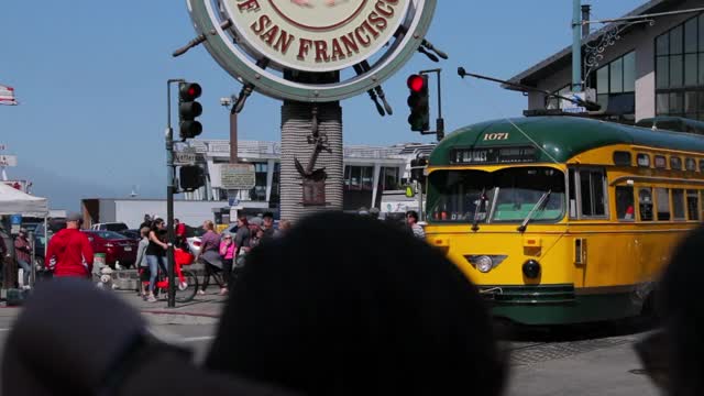 慢镜头向上倾斜拍摄的黄色有轨电车通过的人在城市在阳光明媚的一天-旧金山，加利福尼亚视频素材
