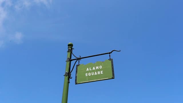 低角度慢动作拍摄的阿拉莫广场标志挂在城市的蓝天-旧金山，加利福尼亚州视频素材