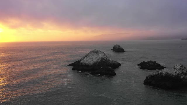 空中平移拍摄的岩石在海上对天空日落，无人机飞过水面-旧金山，加利福尼亚视频素材