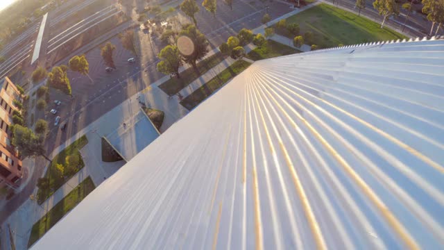 在阳光明媚的蓝天下，在阴影和校园建筑的背景下，空中快速向前移动的瓦尔特金字塔在长滩州立大学的一边视频下载