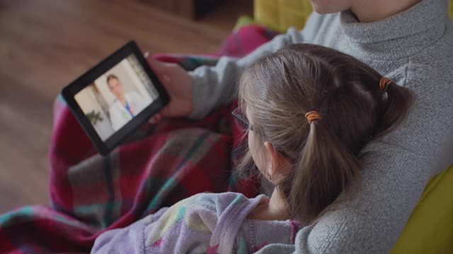 母亲用数字平板电脑与医生，儿科医生沟通她的女儿的疾病视频素材