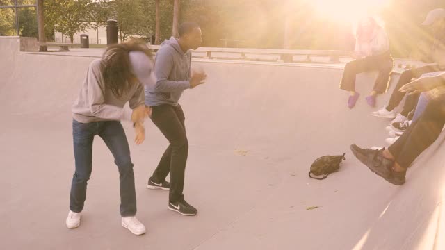 朋友们看着男人在滑板公园跳舞视频素材