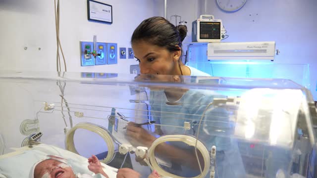拉丁美洲护士在新生儿重症监护室的保育箱里检查啼哭婴儿的生命体征视频素材