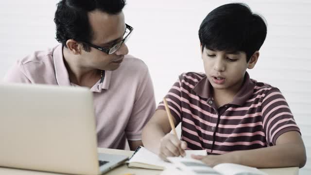 亚洲男孩做家庭作业，在他的父亲的帮助下。视频素材