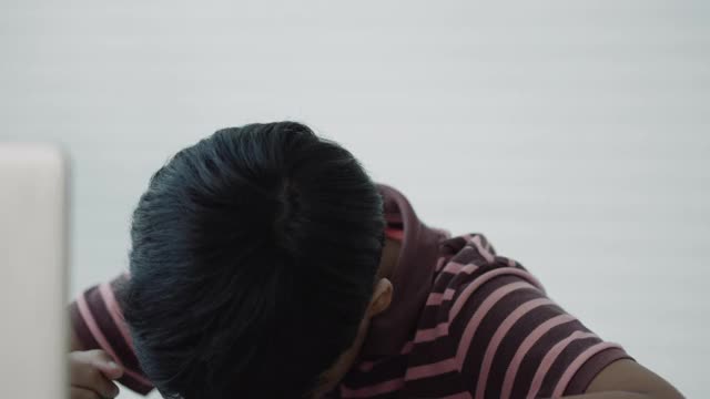 一个亚洲男孩在家自学时使用笔记本电脑进行在线学习视频素材