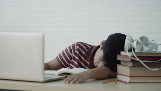一个亚洲男孩在家自学时使用笔记本电脑进行在线学习视频下载