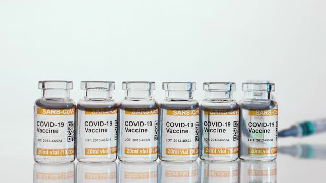 摘要白背景与新冠肺炎疫苗小瓶在低温下淘洗。标记SARS-CoV-2对抗冠状病毒。最后，一个注射器进入了视野视频素材
