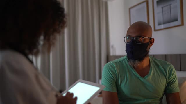医生在病人的居家口罩中使用数字平板电脑视频素材