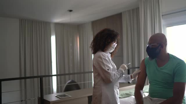 女医生或护士在家为男子接种疫苗-戴口罩视频素材