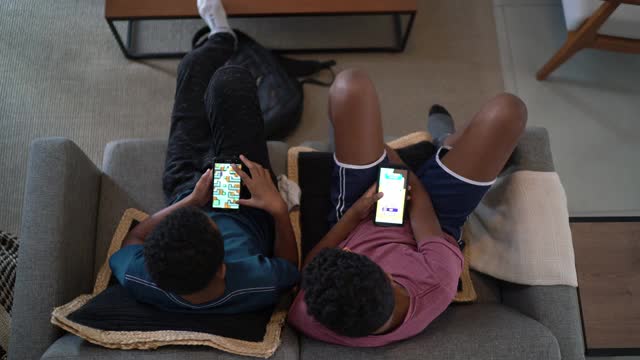 俯视图，兄弟们在客厅用智能手机在家玩游戏视频下载