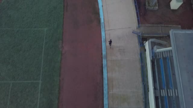 无人机拍摄的一名男子在室内赛车场足球场骑着自行车。视频下载
