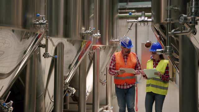 在啤酒厂的生产过程中，一组员工在检查啤酒罐视频素材