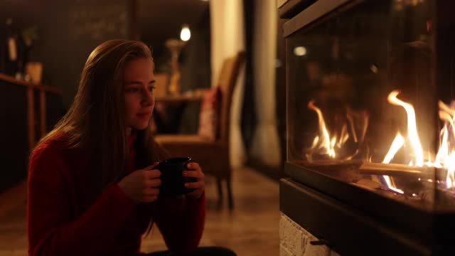 十几岁的女孩在壁炉边享受着一杯热巧克力视频素材