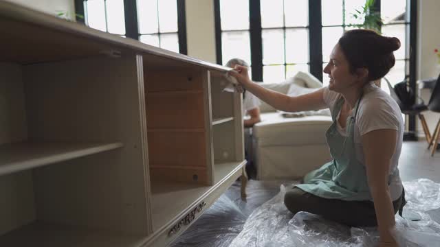 一位年轻女子正在修理旧家具，并在家里享受生活视频下载