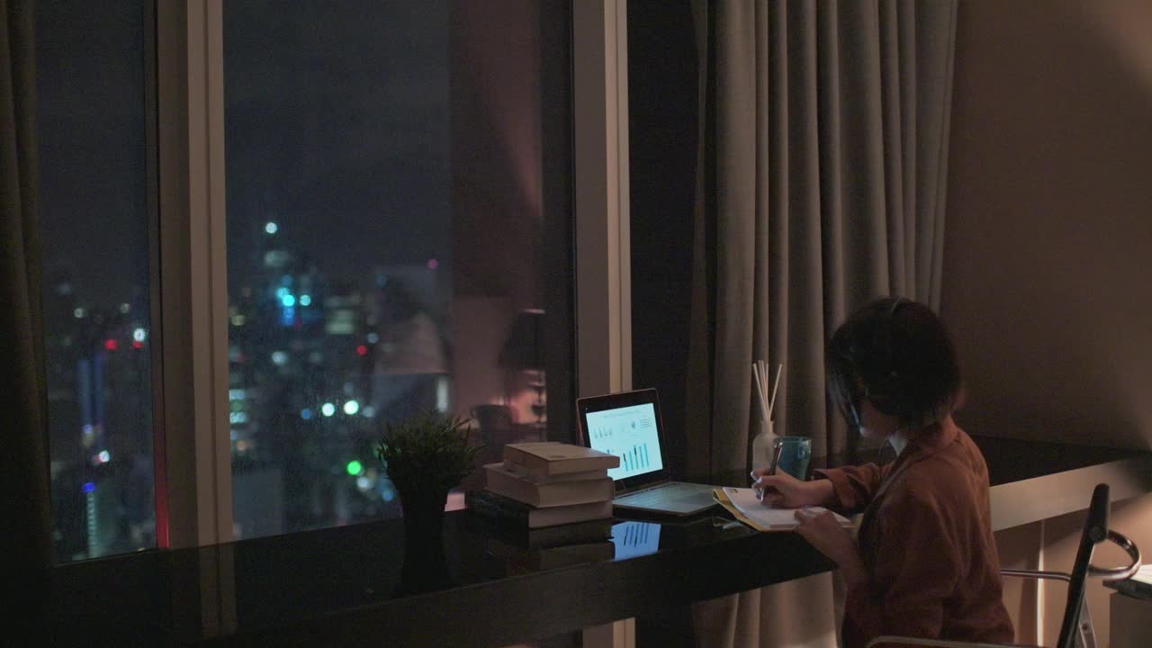 亚洲中国美丽的女人使用笔记本电脑在家工作在书房写作耳机视频素材