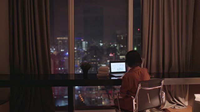 亚洲华人美丽的女人使用笔记本电脑工作，在家自习室书写耳机视频素材