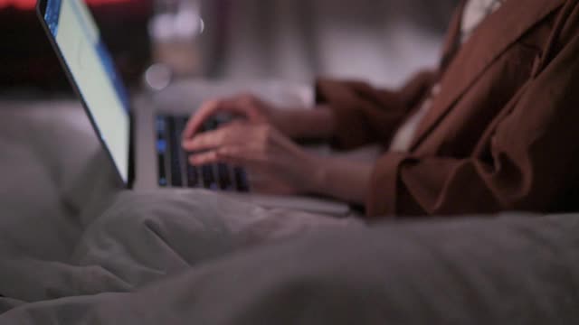 亚洲华裔美女晚上在卧室里用笔记本电脑进行视频通话视频素材