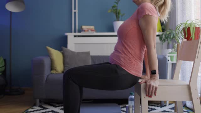 妇女在家里用椅子进行锻炼视频素材