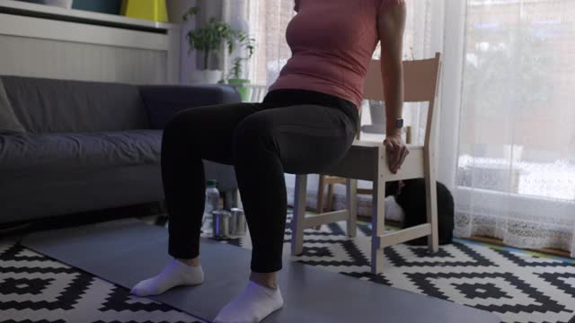 妇女在家里用椅子进行锻炼视频素材