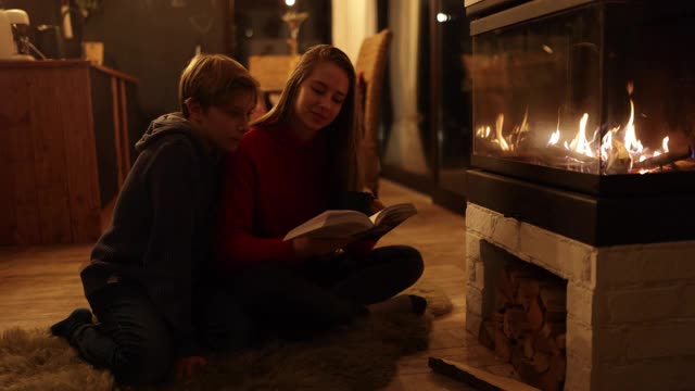 哥哥和妹妹喜欢在壁炉旁看书视频素材
