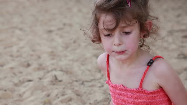 顽皮的小女孩在沙滩上玩沙子视频素材
