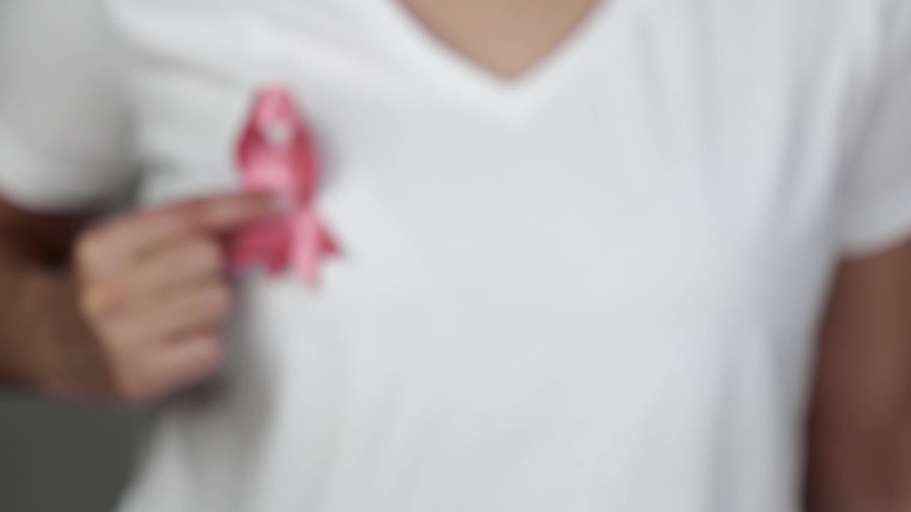 一名妇女向镜头展示了一条粉色的乳腺癌意识丝带视频下载